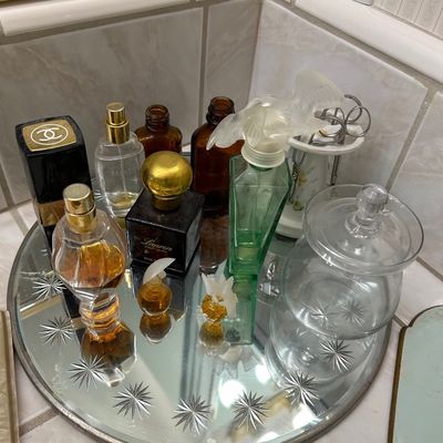 Sale Photo Thumbnail #51: Collection of vintage perfume bottles, including Chanel and Ralph Lauren Lauren, arranged on a starburst-etched round mirror vanity tray.