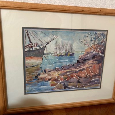 Sale Photo Thumbnail #60: Framed original watercolor painting depicting sailboats and ships in a harbor near a rocky shoreline, presented in a light wood frame with off-white matting.