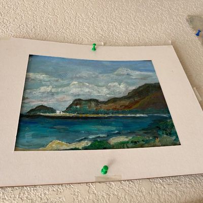 Sale Photo Thumbnail #143: Original matted oil landscape painting depicting a coastal bay and mountains, pinned to a textured wall.