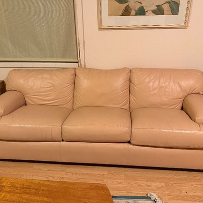 Sale Photo Thumbnail #195: Beige leather three-cushion sofa with plush pillow arms, flanked by wooden side tables with lamps.