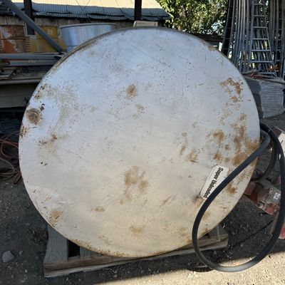 Sale Photo Thumbnail #123: Large circular metal fuel tank labeled 'Super Unleaded', showing surface rust and wear, resting on a wooden pallet.