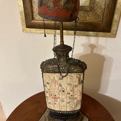Sale Photo Thumbnail #27: Ornate Asian-style table lamp featuring carved panel scenes, faux turquoise embellishments, and a red dome shade with raised metal dragon motif.