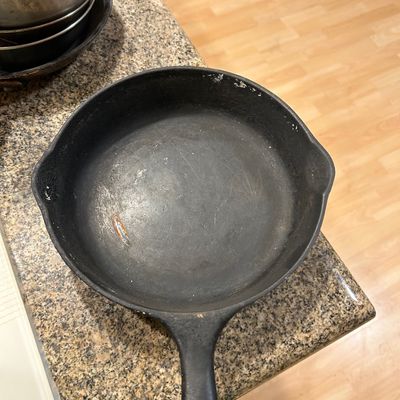 Sale Photo Thumbnail #33: Vintage cast iron skillet with dual pour spouts resting on a countertop, showing minor surface wear and patina.