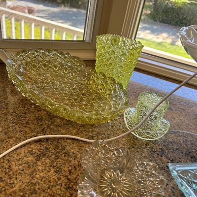 Sale Photo Thumbnail #25: Collection of yellow Vaseline glass items in a daisy and button pattern, including a oval serving dish, a tumbler, and a small top hat novelty piece.