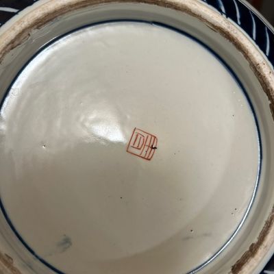 Sale Photo Thumbnail #2: Underside of a Asian porcelain vessel showing a red square character mark and unglazed foot rim.