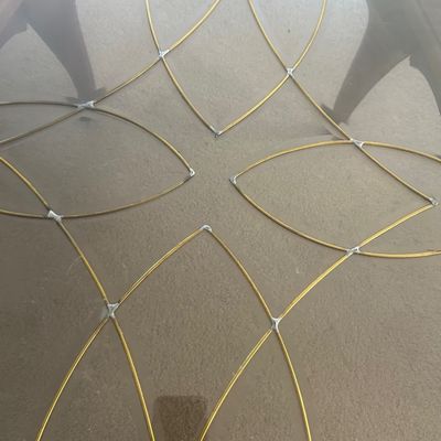 Sale Photo Thumbnail #187: Glass table top featuring an intricate gold wire overlay design in a geometric floral pattern.