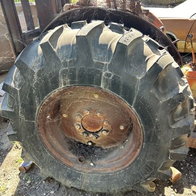Sale Photo Thumbnail #121: Vintage tractor or forklift with a large Denman Industrial Tractor tire, showing heavy cobwebs and rust on the metal wheel rim.