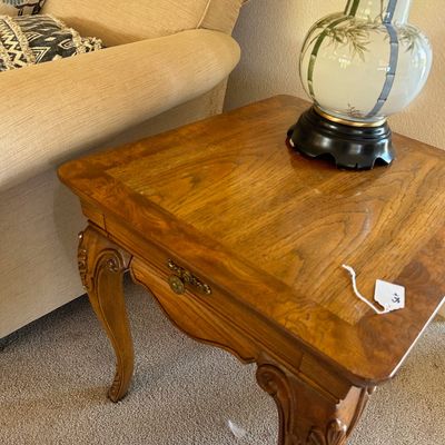 Sale Photo Thumbnail #190: French Provincial style wood end table with carved cabriole legs and brass hardware, alongside an Asian-inspired hand-painted ceramic lamp.