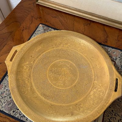 Sale Photo Thumbnail #62: Vintage round brass tray featuring integrated side handles and an intricate etched floral center pattern.