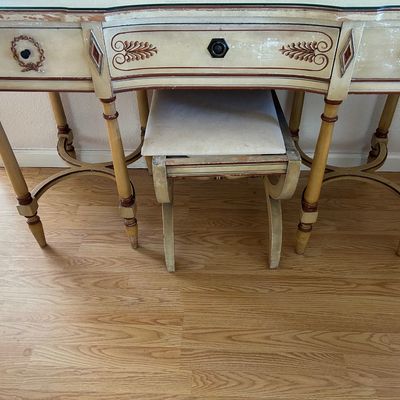 Sale Photo Thumbnail #181: French Provincial style distressed vanity desk with matching upholstered stool, featuring three drawers with decorative painted accents.