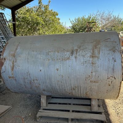 Sale Photo Thumbnail #122: Large horizontal steel storage tank resting on wooden pallets, showing surface wear and minor rust.