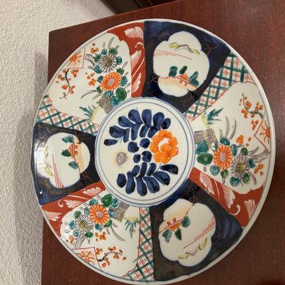 Sale Photo Thumbnail #100: Vintage Japanese Imari style porcelain charger plate featuring hand-painted floral motifs and geometric paneled patterns in cobalt blue, rust red, and green.