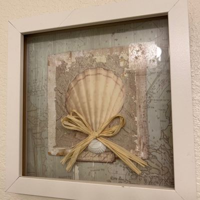 Sale Photo Thumbnail #69: Framed coastal shadowbox wall art featuring seashell, raffia bow, and nautical chart background in a white square frame.