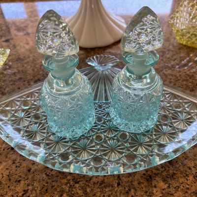 Sale Photo Thumbnail #24: Pair of light blue pressed glass perfume bottles with stoppers resting on a matching fan-shaped vanity tray.