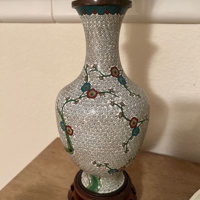 Sale Photo Thumbnail #71: Vintage Chinese cloisonné enamel vase on a carved wooden base, featuring a white swirl ground with delicate floral and vine motifs.