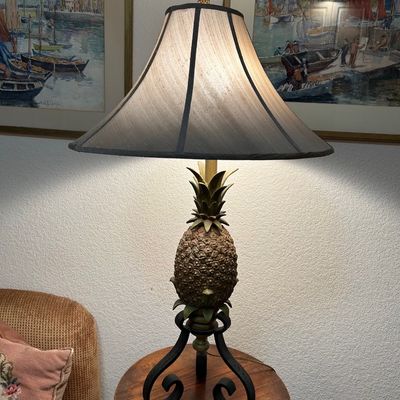 Sale Photo Thumbnail #53: Tropical-style pineapple table lamp featuring a textured resin pineapple body on a black scrollwork metal base, complete with a fabric bell shade and a pineapple finial.
