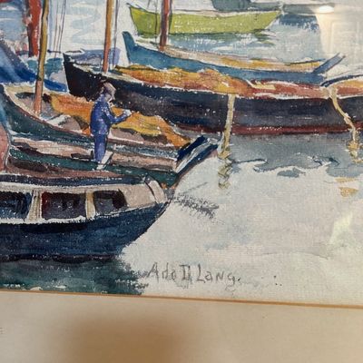 Sale Photo Thumbnail #55: Framed watercolor painting depicting a harbor scene with colorful fishing boats, signed Adolf Lang in the lower corner.