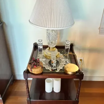 Sale Photo Thumbnail #24: Traditional dark wood two-tier side table displaying a cut crystal table lamp, glass candlesticks, and decorative boxes.