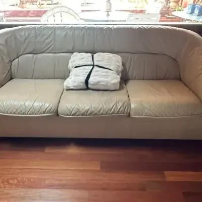 Sale Photo Thumbnail #27: Vintage off-white leather three-cushion sofa featuring rounded, padded arms and a textured white throw blanket.