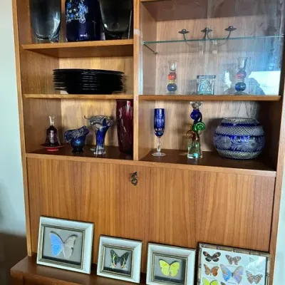 Sale Photo Thumbnail #17: Mid-century Danish modern teak hutch and wall unit filled with assorted glassware, ceramics, and framed butterfly specimens.
