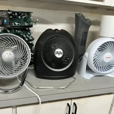 Sale Photo Thumbnail #8: Collection of small electric appliances including Vornado and Honeywell air circulator fans, a mini tower heater, and spools of Christmas string lights.