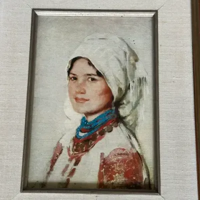 Sale Photo Thumbnail #37: Framed portrait oil painting depicting a young woman in traditional Eastern European attire, set within a linen mat and gilt wooden frame.