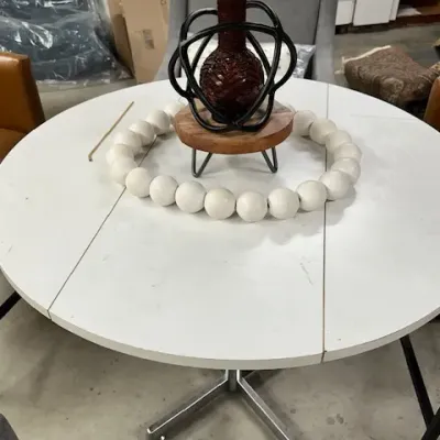 Sale Photo Thumbnail #5: Modern white round pedestal dining table, styled with decor including a textured vase on a elevated riser and large white beaded garland.