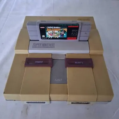 Vintage Super Nintendo Entertainment System (SNES) console showing typical plastic yellowing, loaded with a Super Mario All-Stars game...