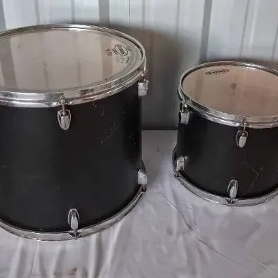 Pair of black drum set tom drums with chrome hardware, featuring Evans drumheads.