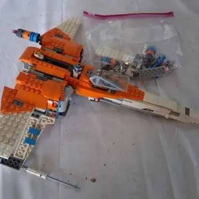 Assembled Lego Star Wars Poe's X-Wing Fighter set with extra pieces stored in a clear plastic bag.