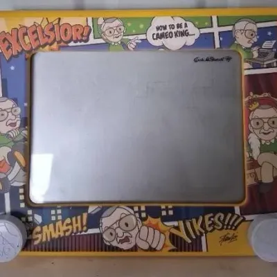 Stan Lee novelty Etch A Sketch toy featuring colorful comic-style graphics and Stan Lee caricatures around the frame.
