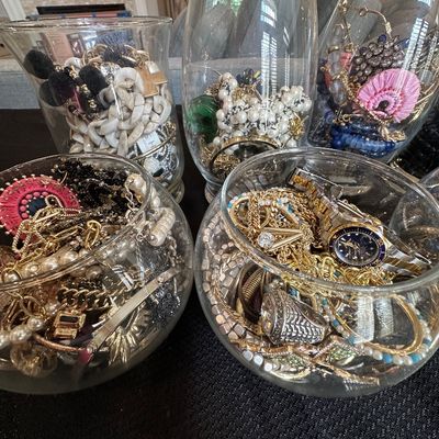 Sale Photo Thumbnail #6: Collection of glass vases and bowls filled with an assortment of costume jewelry, watches, and beaded necklaces.