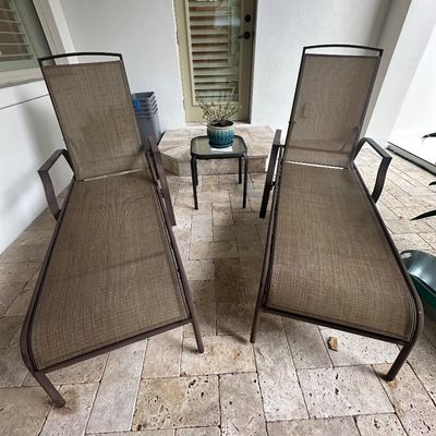 Sale Photo Thumbnail #25: Pair of outdoor mesh sling lounge chairs with dark metal frames, accompanied by a small matching side table.