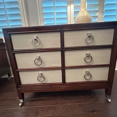 Sale Photo Thumbnail #98: Modern Hollywood Regency style six-drawer chest featuring dark wood framing, light beige drawer fronts, large silver-tone ring pulls, and caster feet.