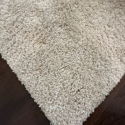 Sale Photo Thumbnail #68: Off-white plush high-pile shag area rug displayed on a dark wood floor.