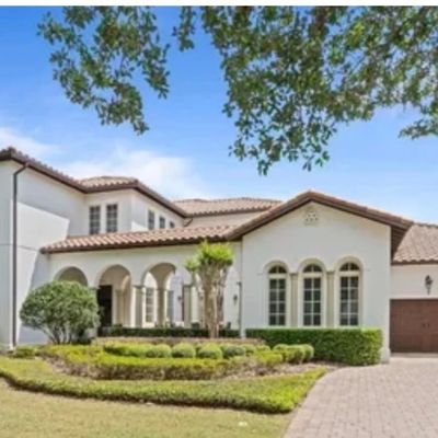 Sale Photo Thumbnail #3: Exterior view of a large Mediterranean-style stucco estate home with a clay tile roof, arched entryway, and brick paver driveway.