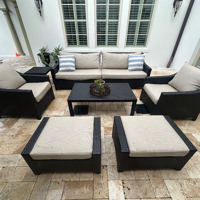 Sale Photo Thumbnail #19: Contemporary dark espresso resin wicker outdoor seating set, including a sofa, two armchairs, two ottomans, a coffee table, and a side table with beige cushions.