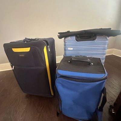 Sale Photo Thumbnail #74: Collection of modern luggage, including a black and yellow Nautica soft-side suitcase, a light blue hardshell spinner, and a blue upright duffel bag.