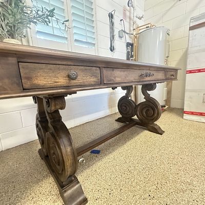 Sale Photo Thumbnail #95: Spanish Revival style dark wood sofa table featuring ornate carved scroll pedestal legs and three drawers with metal pulls.