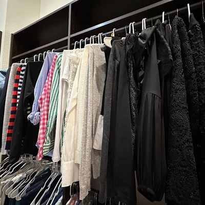 Sale Photo Thumbnail #59: Walk-in closet filled with assorted women's clothing, including tops, sweaters, and jackets hanging on racks.