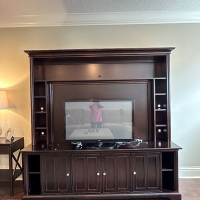 Sale Photo Thumbnail #61: Large dark espresso wooden entertainment center wall unit featuring lower cabinet storage and open side shelving, housing a flat-screen television.