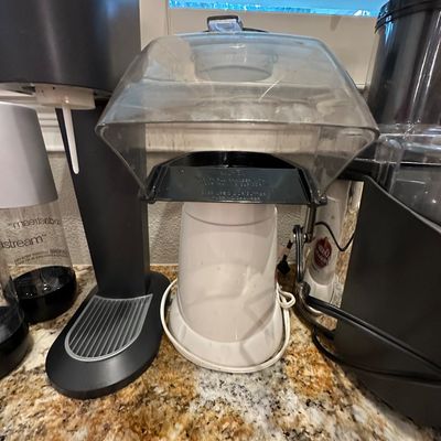 Sale Photo Thumbnail #44: Vintage white electric hot air popcorn popper with clear plastic hood chute, set on a granite countertop alongside other small kitchen appliances.