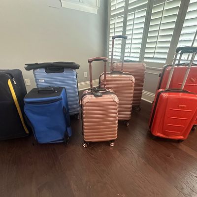 Sale Photo Thumbnail #73: Collection of modern rolling luggage and carry-on suitcases in various colors, including rose gold, red, blue, and black.