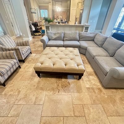 Sale Photo Thumbnail #12: Living room furniture set including a light gray sectional sofa, a large cream-colored button-tufted leather ottoman coffee table, and two striped armchairs.