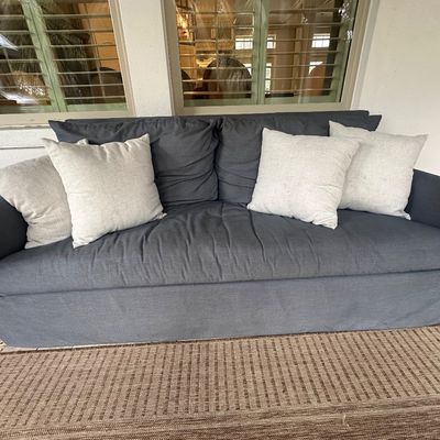 Sale Photo Thumbnail #24: Contemporary dark blue slipcovered outdoor sofa with matching back cushions and four contrasting light gray throw pillows.