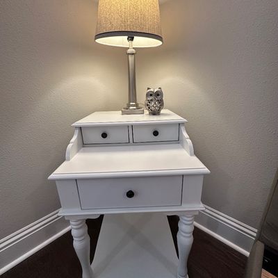 Sale Photo Thumbnail #67: White painted wooden nightstand or telephone table featuring a lower shelf, single drawer, and two small upper drawers. Topped with a brushed nickel table lamp with a heathered fabric shade and a decorative metal owl figurine.