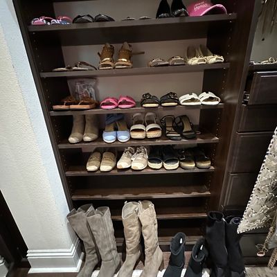 Sale Photo Thumbnail #60: A tall dark wood closet shelving unit organized with various women's footwear, including sandals, heels, sneakers, and tall suede and black boots.