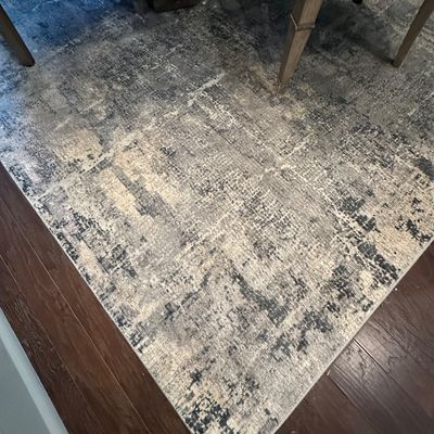Sale Photo Thumbnail #107: Modern abstract area rug in shades of grey, cream, and charcoal, positioned under a dining table and chairs on dark hardwood flooring.