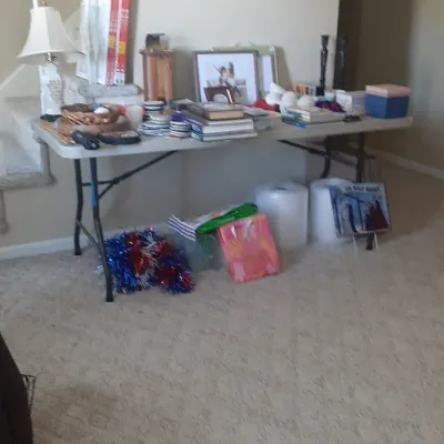 Folding display table filled with various home decor items, books, picture frames, lamps, and holiday decorations.