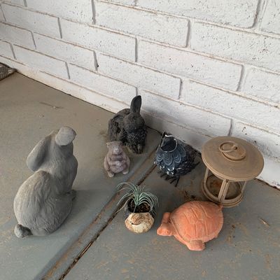 Sale Photo Thumbnail #132: Collection of outdoor garden decor including concrete and resin rabbit figurines, a quail sculpture, a terracotta turtle, a small potted planter, and a metal lantern.
